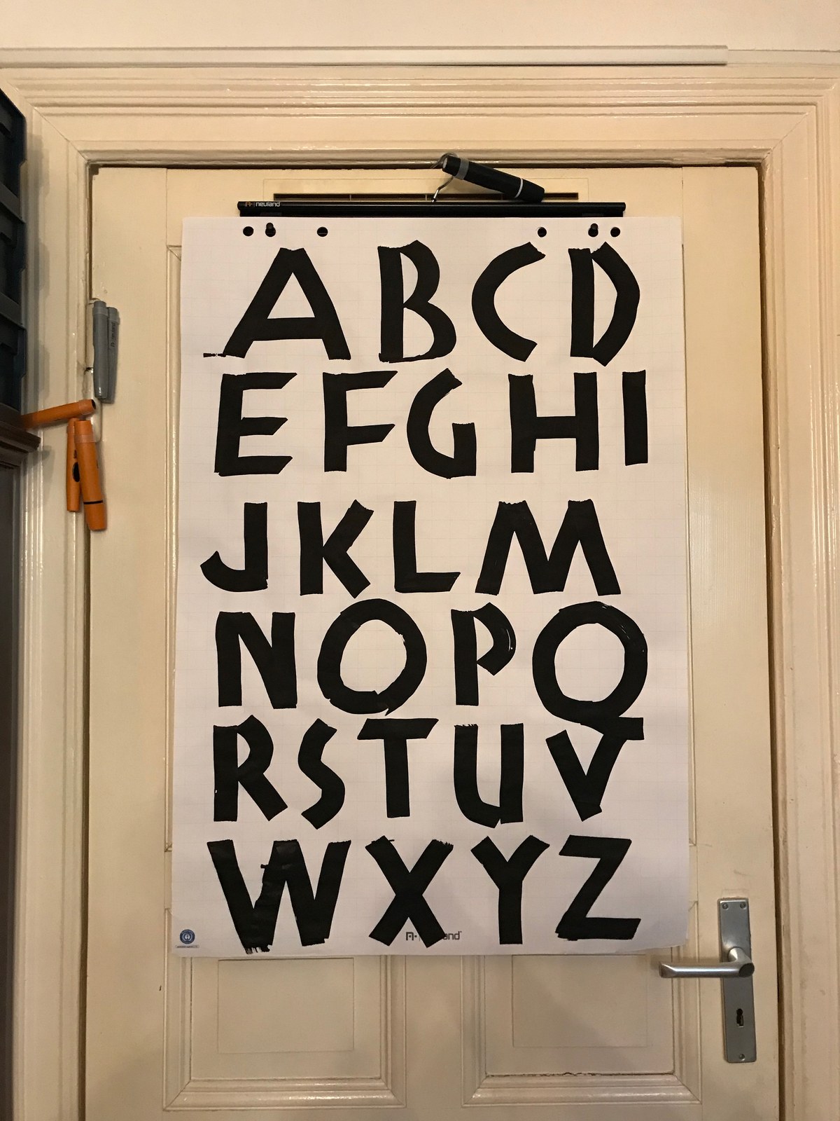 A flipchart sheet mounted on a door, filled with large black capital letters.