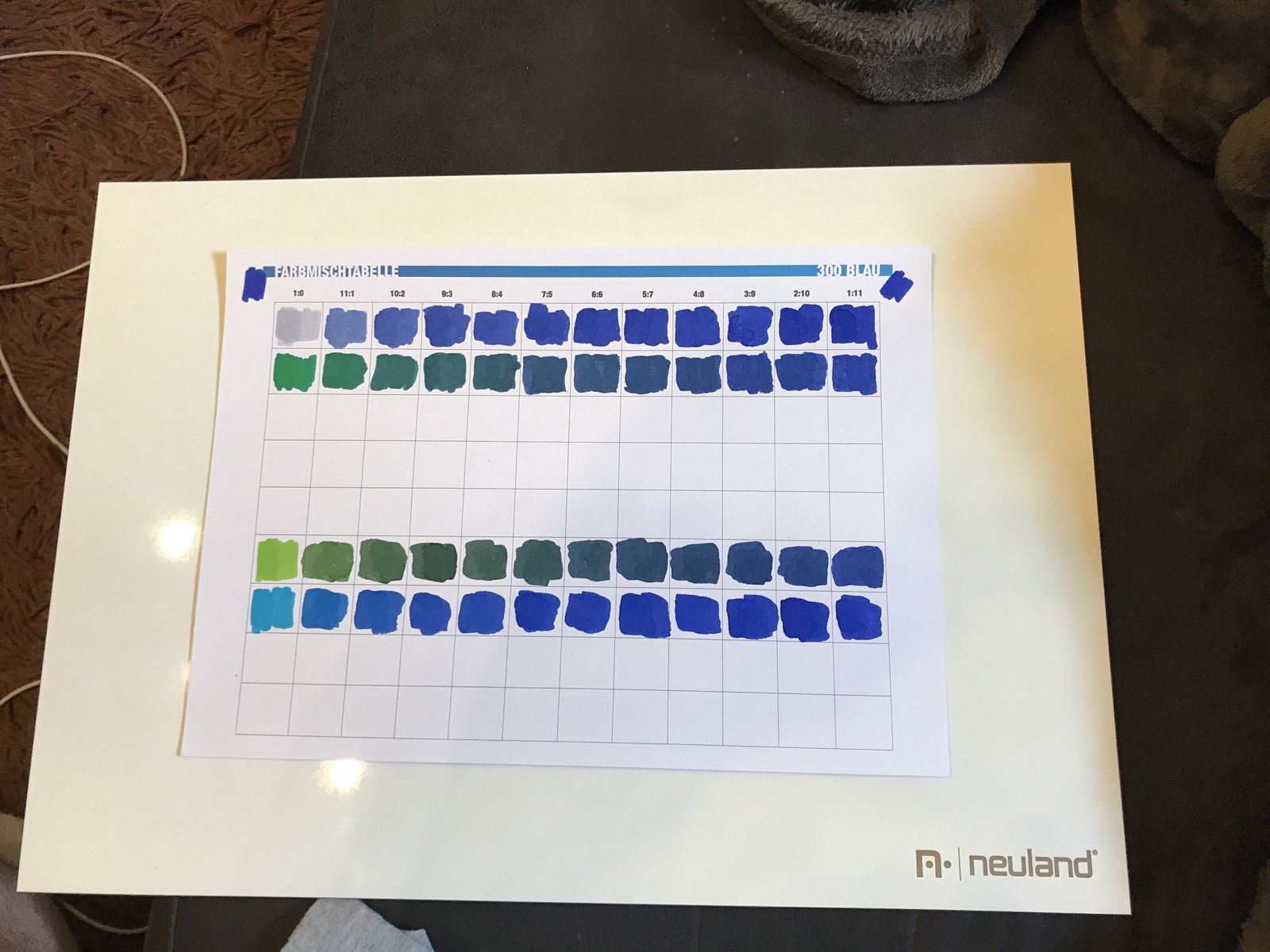 A printed blue mixing table filled with graduated rows of painted swatches.