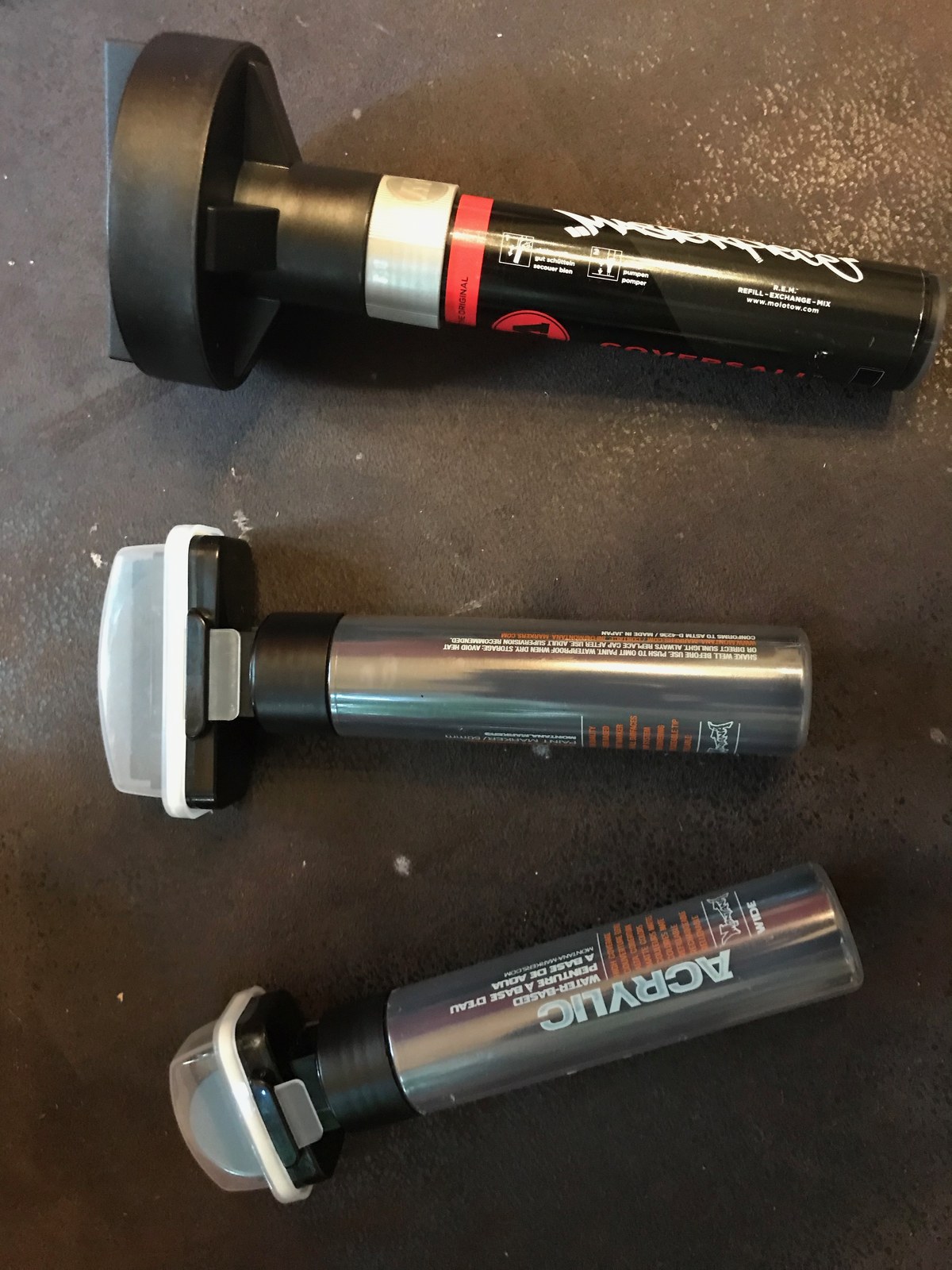 Three broad markers laid on a dark surface with their wide flat nibs exposed.