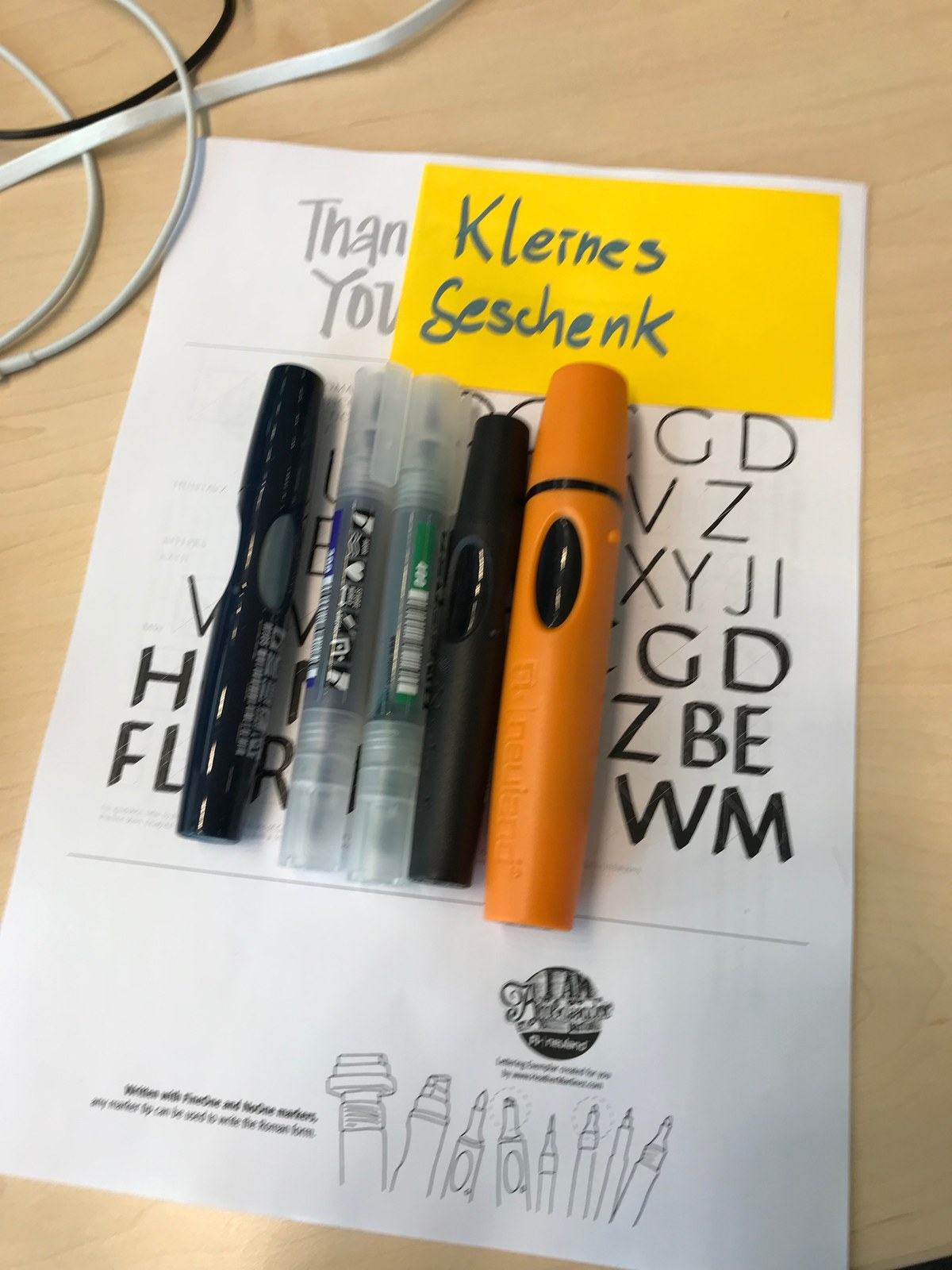 A small selection of markers laid on a printed lettering practice sheet.